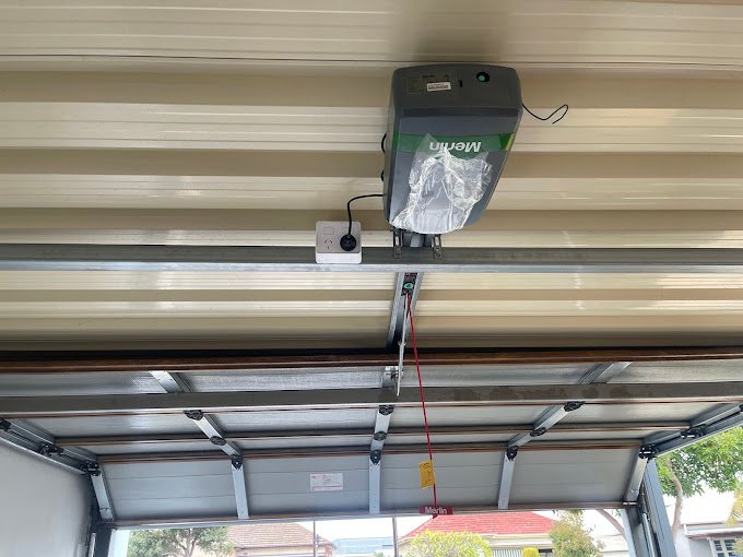 Garage door motor mounted on the ceiling with a red safety cord.
