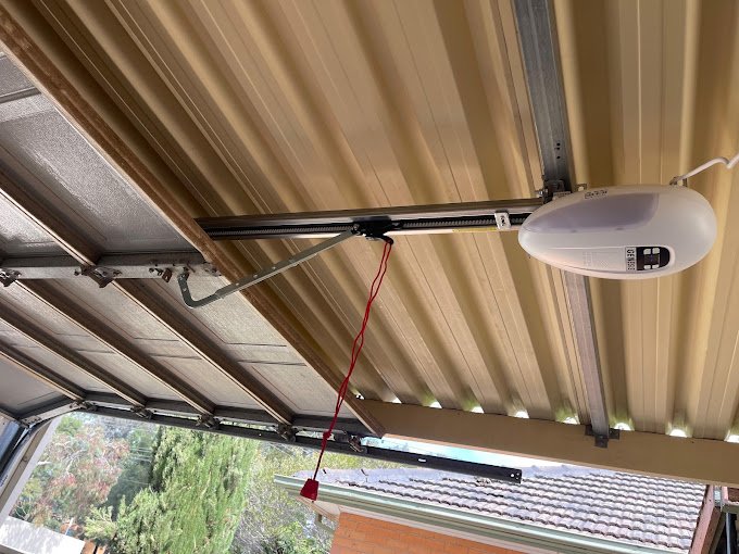 Garage door motor installed on the ceiling with red safety cord.